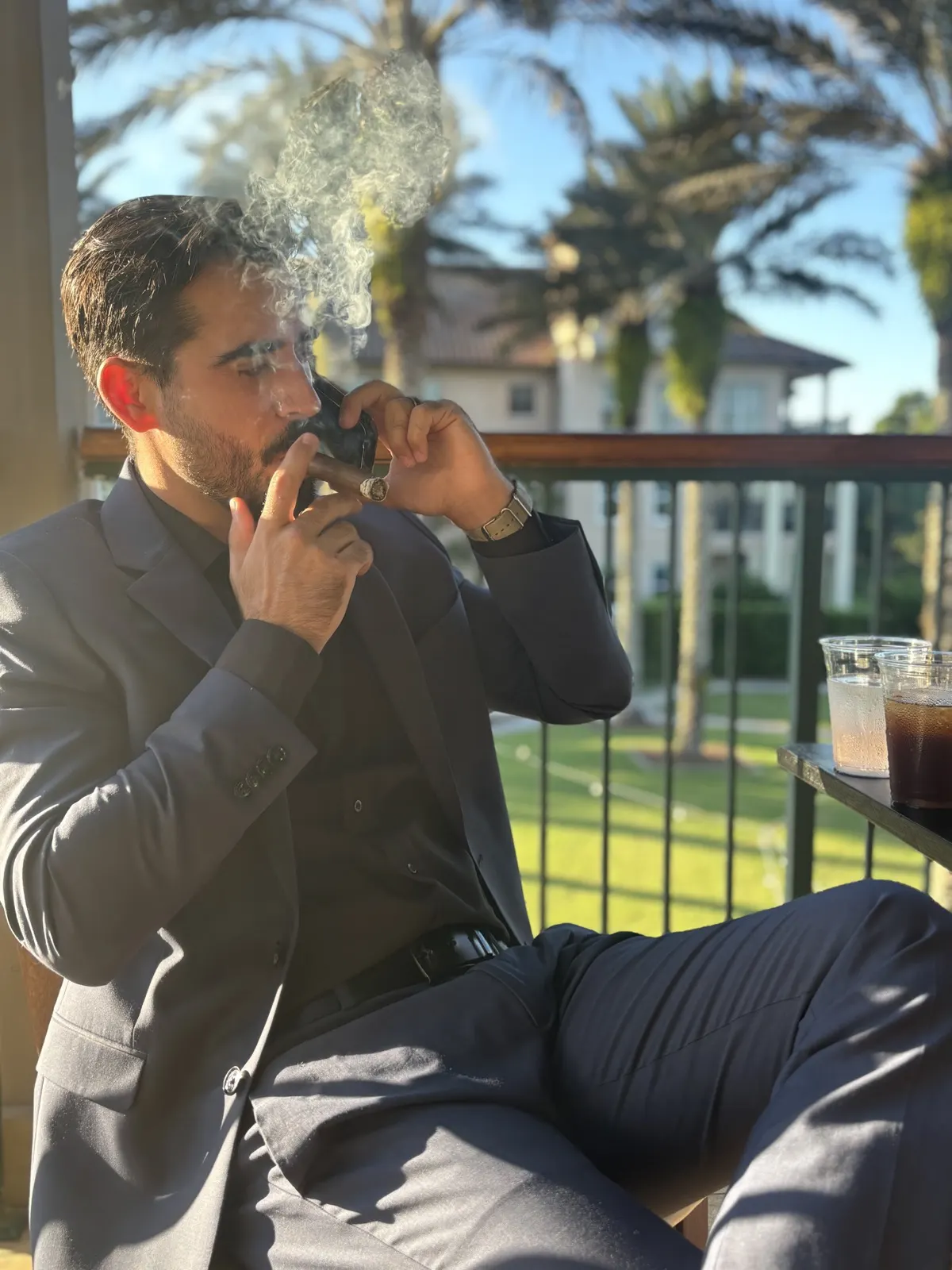 Guest enjoying a cigar on a balcony overlooking palms