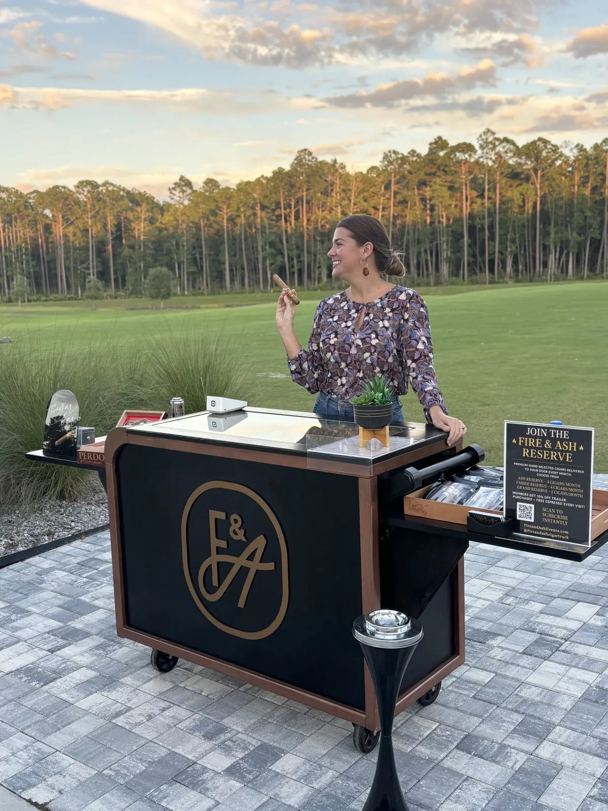 Attendant serving guests at the Fire and Ash cigar bar during sunset