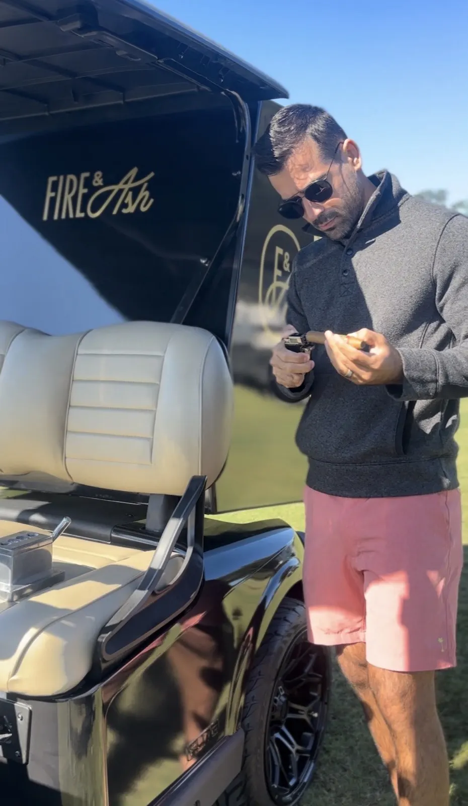 Golfer enjoying a cigar beside the Fire and Ash cart