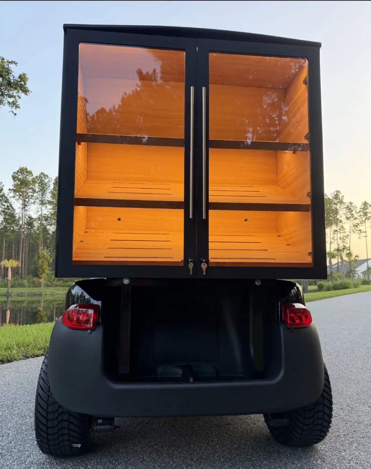 Rear of the Fire and Ash golf cart humidor with lit cedar shelves behind glass doors