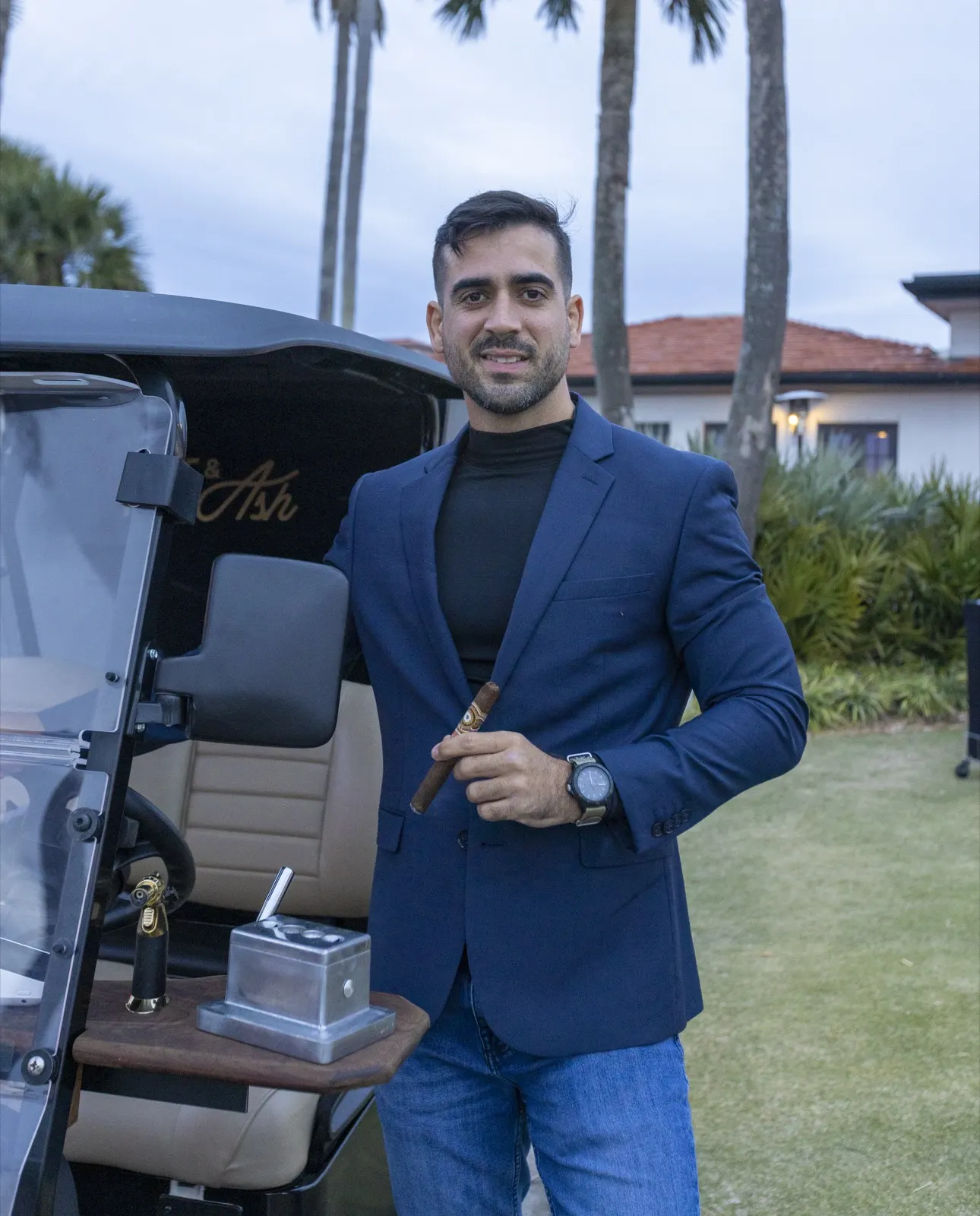 Carlos Lopez standing proudly beside the cigar golf cart