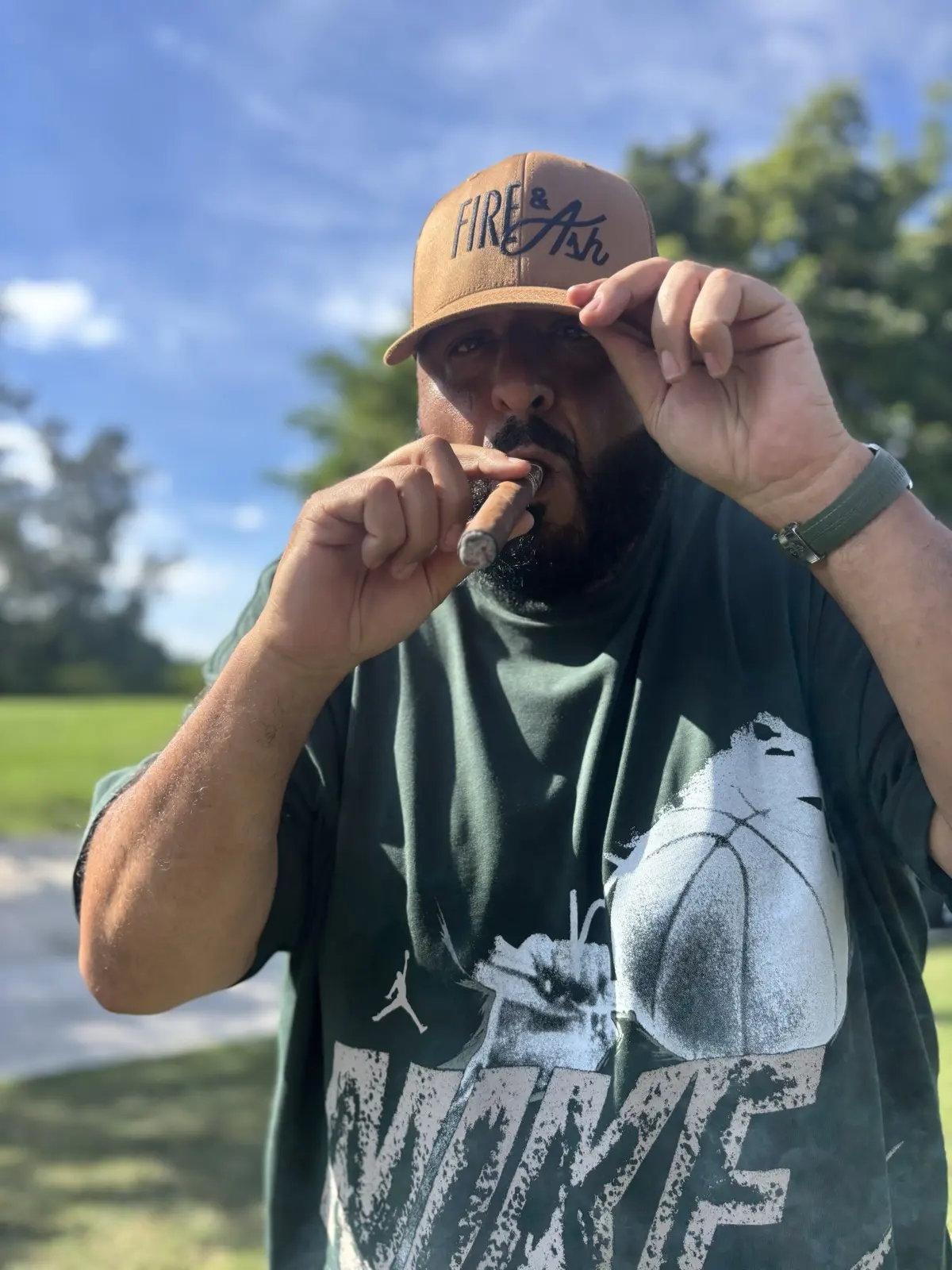 Guest in a Fire and Ash cap lighting a cigar outdoors