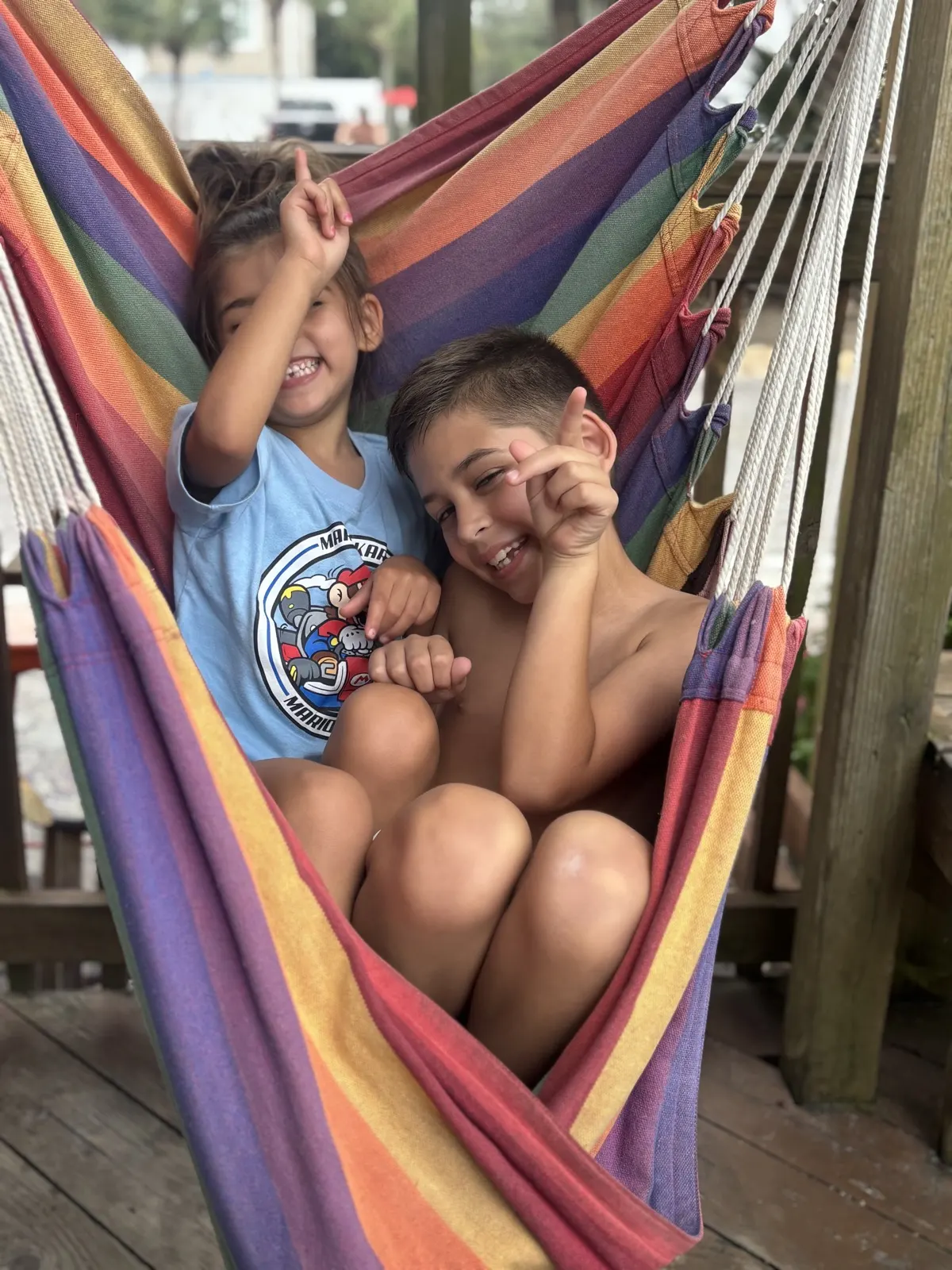 The Lopez kids laughing in a rainbow hammock