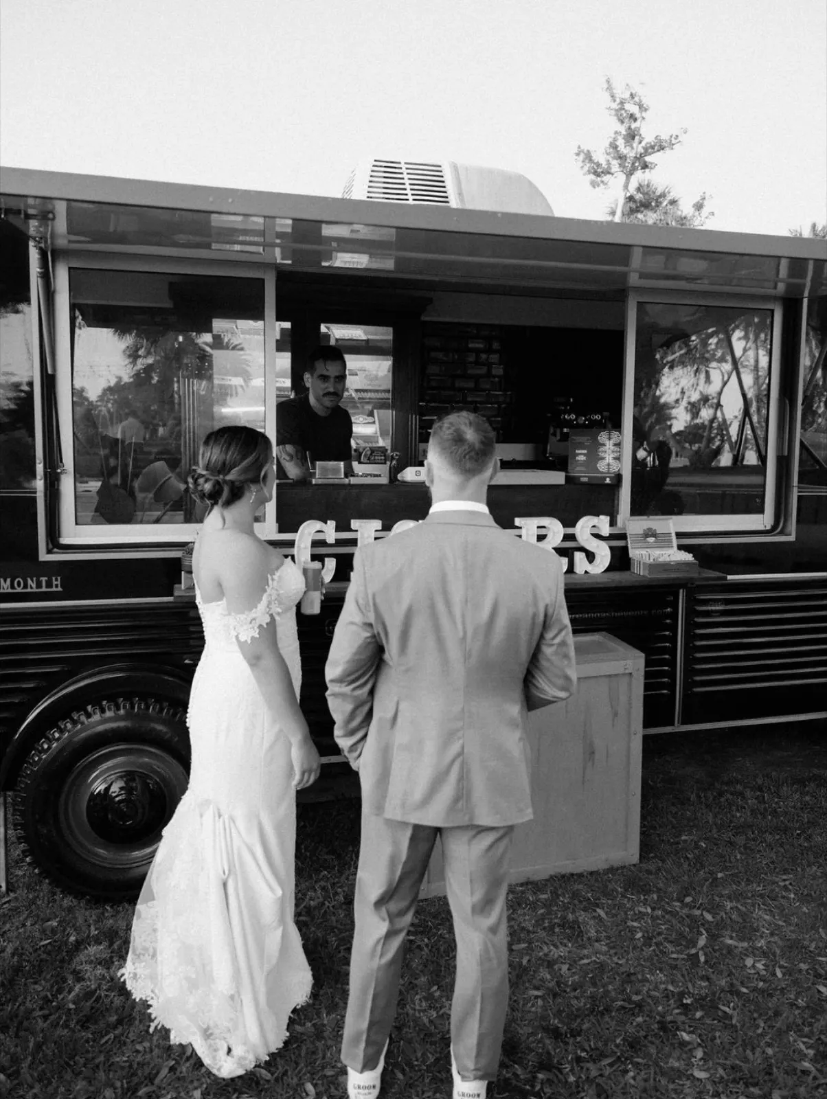 Black and white photo of newlyweds at the cigar truck window
